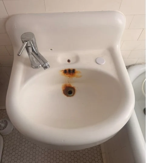 Rust-stained bathroom sink before refinishing